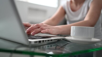 Technology, video conference, virtual event concept - unrecognizable woman with coffee typing working with laptop computer at home during coronavirus quarantine. Remote distance work education