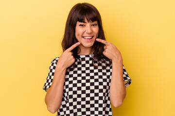 Young caucasian woman isolated on yellow background smiles, pointing fingers at mouth.