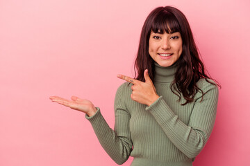 Young caucasian woman isolated on pink background excited holding a copy space on palm.