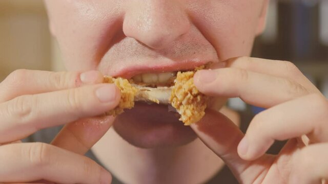 Young Man Eating Chicken Wing Fast Food Close Up.