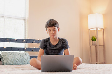 Distance learning online education. Schoolboy studies at home and does school homework. Concept of home education and distance learning. Boy resting and watching a movie in his free time.