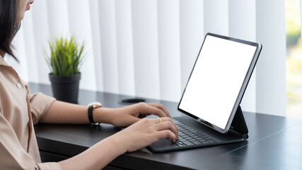 Close-up of a businesswoman working on a tablet with a blank white screen in the office. Mock up.