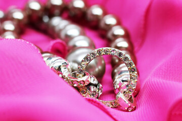 A bracelet made of beads and diamonds on a pink dress