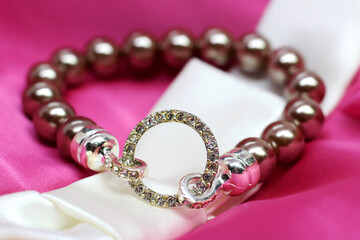 Beige bead bracelet on a pink textiles