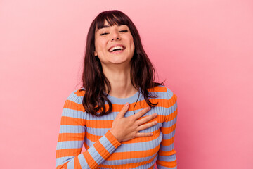 Young caucasian woman isolated on pink background laughs out loudly keeping hand on chest.