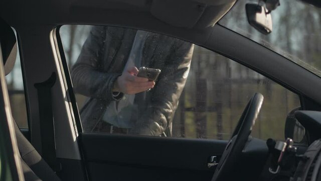 Man unlocks car door with phone app. View from the car interior