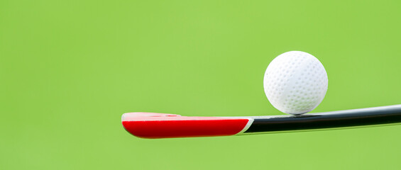 Field hockey stick and ball on green background. Professional sport concept