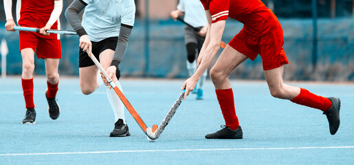 Two field hockey player, fighting for the ball on the midfield during an intense match on green...