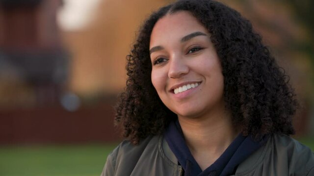 Beautiful mixed race African American girl biracial teenager young woman outside smiling and laughing outside in a park