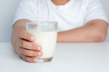 Fototapeta na wymiar Fat boy holding a full glass of milk. Children are drinking milk. The concept of healthy eating It is beneficial for the growth of children.