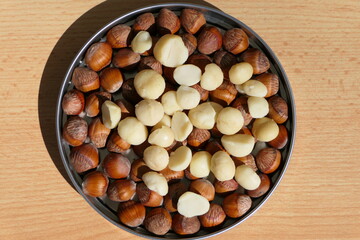 Shelled macadamia nuts, also called Queensland nut or Hawaii nut, in a tin with hazelnuts