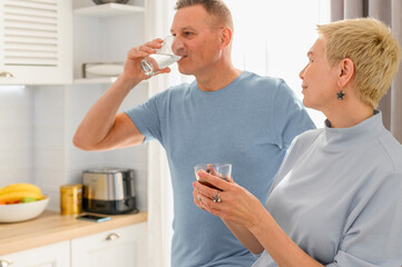 Healthy senior couple drink water. Holds a glasses of water