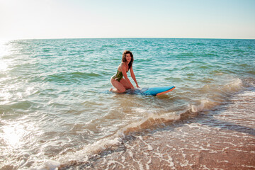 Beautiful sport woman holding the surfboard in the beach and relaxing after surfing on vacation