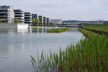 Park named Glattpark with apartment buildings, pond and metal pedestrian bridge at City of Opfikon...