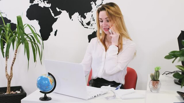 Happy businesswoman travel agent using smartphone for communication and work on-line in modern office with plants, booking flight. Travel agency arranging tour, having calls worldwide