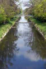 River Glatt at springtime with pedestrian bridge in the background and reflections in water. Photo taken April 30th, 2021, Rumlang, Switzerland.