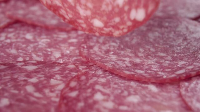Fork takes a slice of sliced fresh salami sausage close-up. Macro. Dolly shot. Eating a deli meat