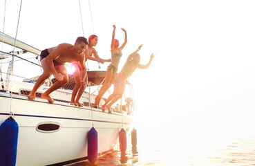 Side view of young crazy friends jumping from sailboat on sea ocean trip - Men and women having...