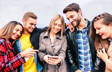 Milenial friends on fun moment using mobile smart phone - Young people always connected at social media devices - Technology concept with modern teenagers sharing content online - Bright vivid filter