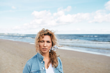Fototapeta na wymiar ,BEAUTIFUL NATURAL BLOND GIRL BY THE SEA, BOKEH PORTRAIT, SUNSET ON THE BEACH, denim jacket