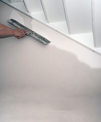 .Hand of builder worker spacks wall with putty plaster aligning wallwith spatula. Renovation and...
