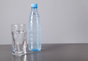 Water bottle and glass, on gray background.