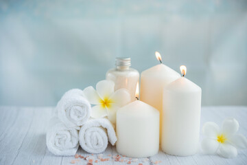 Fototapeta na wymiar Spa coconut products on light wooden background. Composition with towels, flowers and salt, candle on massage table in spa salon