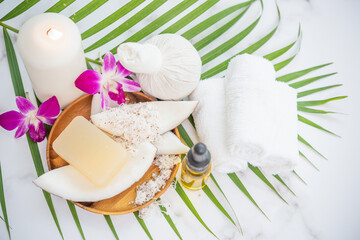 Coconut oil, tropical leaves and fresh coconuts. Spa coconut products on light wooden background. Spa still life of organic cosmetics with coconuts on a light wooden background, body care concept.