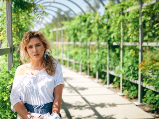 beautiful natural girl against the background of a green tunnel full of flowers and plants