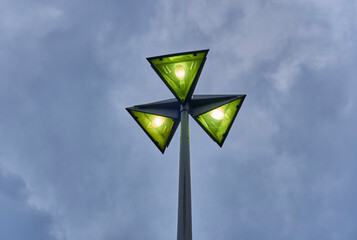 Lamppost with 3 triangular lights over sky with clouds