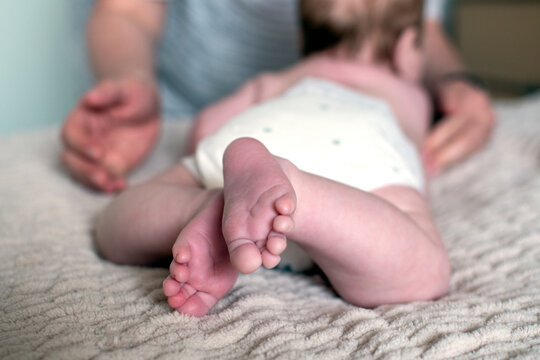 Close up of a baby feet. Mother's hands in the foreground. Childcare concept. Selective focus