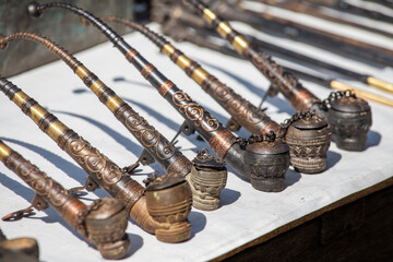 Handmade decorative smoking pipes for opium and other souvenir in a tourist stall on street market in Burma, Myanmar - obrazy, fototapety, plakaty