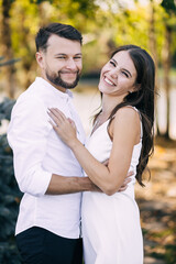 Fototapeta premium smiling beautiful girl and her handsome boyfriend. Woman in a white silky dress. Happy cheerful family.