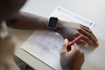 High angle closeup of unrecognizable African-American boy writing in notebook while taking math test in school, focus on smartwatch, copy space - obrazy, fototapety, plakaty