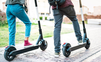 Close up of city commuters using electric scooter at urban park - Millenial students riding new...