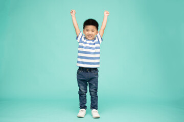 Cute Asian boy showing winner sign with his hands up isolated on green background