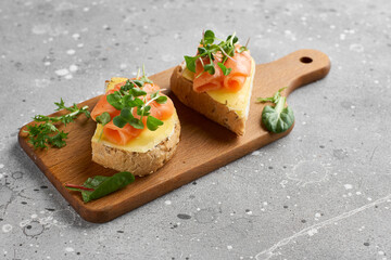 Bruschetta with salmon. Whole grain bread with salmon, cheese on a wooden board.