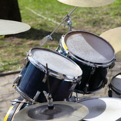 Old drum kit on green grass and stone pavement background, outdoor street music entertainment