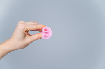 Woman holding folded menstrual cup on white background.