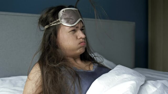 Young woman waking up suffering headache and hangover after drinking alcohol.