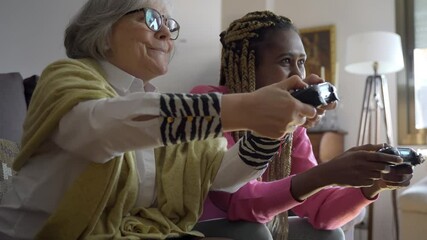 Multi generational senior and young woman playing video games at home - Multiracial people having fun with technology trends