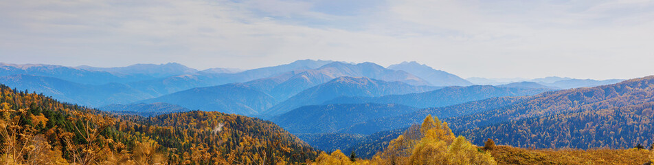 Autumn blue sky with white clouds and mountains on the yellowed vegetation