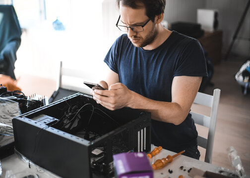 Portrait Of A Handsome Nerd Man Is Servicing Computer Motherboard And Cooler.