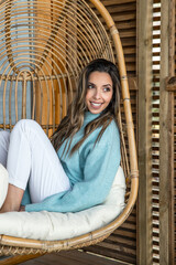 Cheerful woman resting in wicker hanging chair
