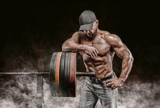 Muscular bearded man stands near the barbell. Bodybuilding, fitness, powerlifting concept.