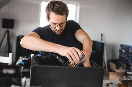 portrait of a handsome nerd man is servicing Computer motherboard and cooler.