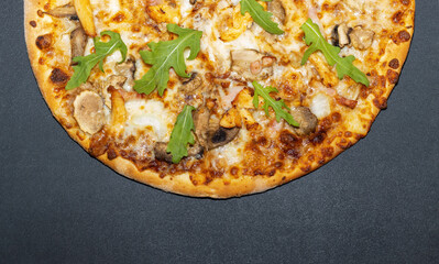Top view of half toasted delicious pizza with cheese and arugula on gray table background, place for text.
