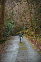 Obraz premium Woman walking along road in forest