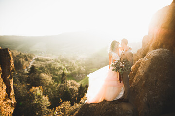 Happy beautiful wedding couple bride and groom at wedding day outdoors on the mountains rock. Happy marriage couple outdoors on nature, soft sunny lights