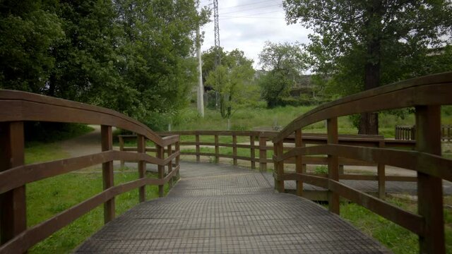 brown wooden bridge in the middle of nature on a path to cross a river. rural structure for ecological trail. country road with decorative wooden walkways.